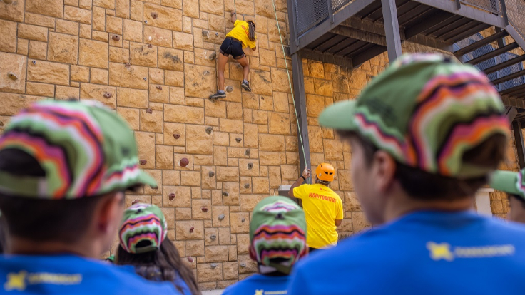 Infants miren com una noia puja per un rocòdrom Infants miren com una noia puja per un rocòdrom